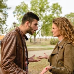 man and woman facing each other arguing in a park