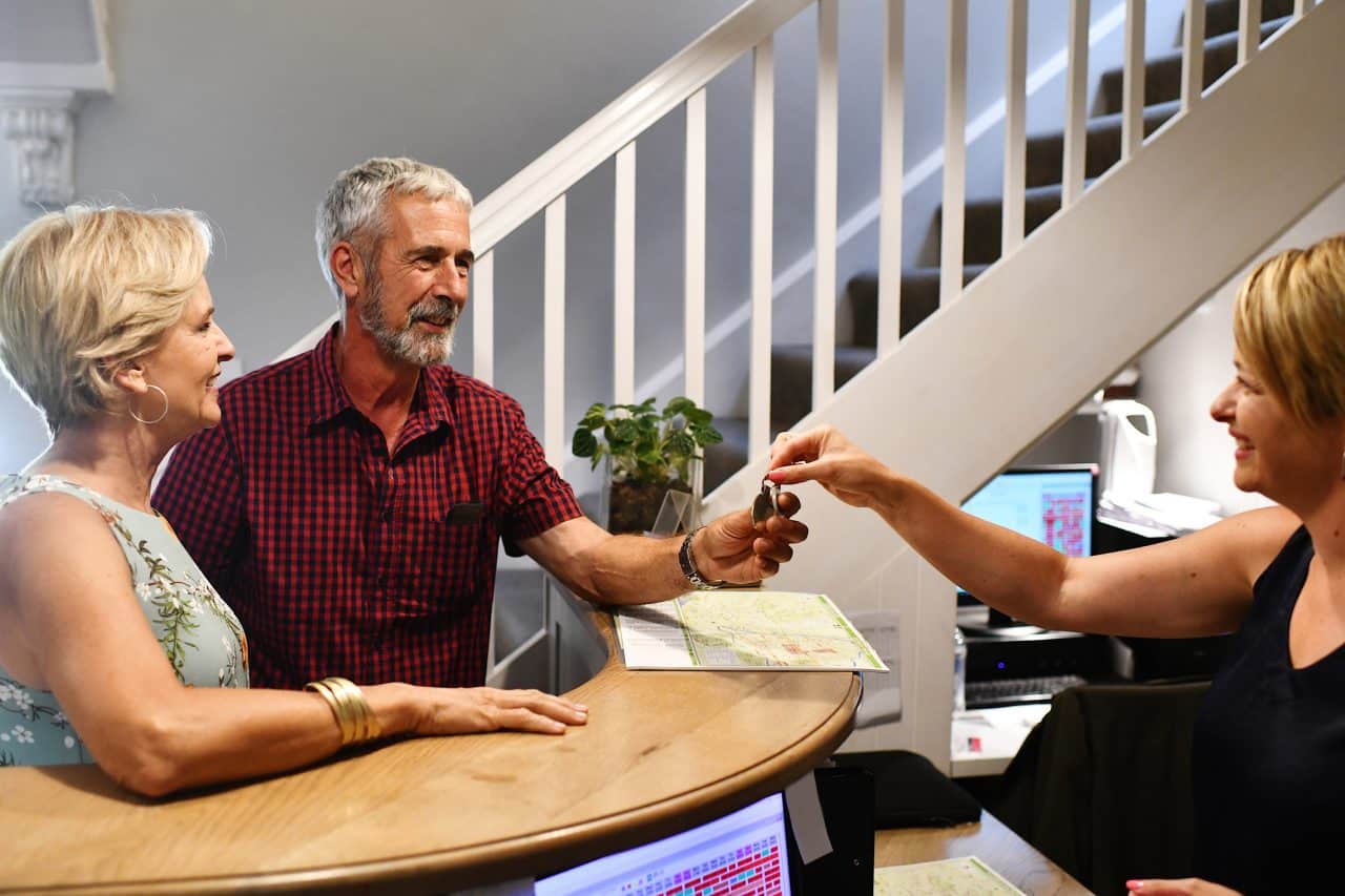 A Caucasion couple checking in a reception being friendly with the receptionist. They are getting the room key from her.