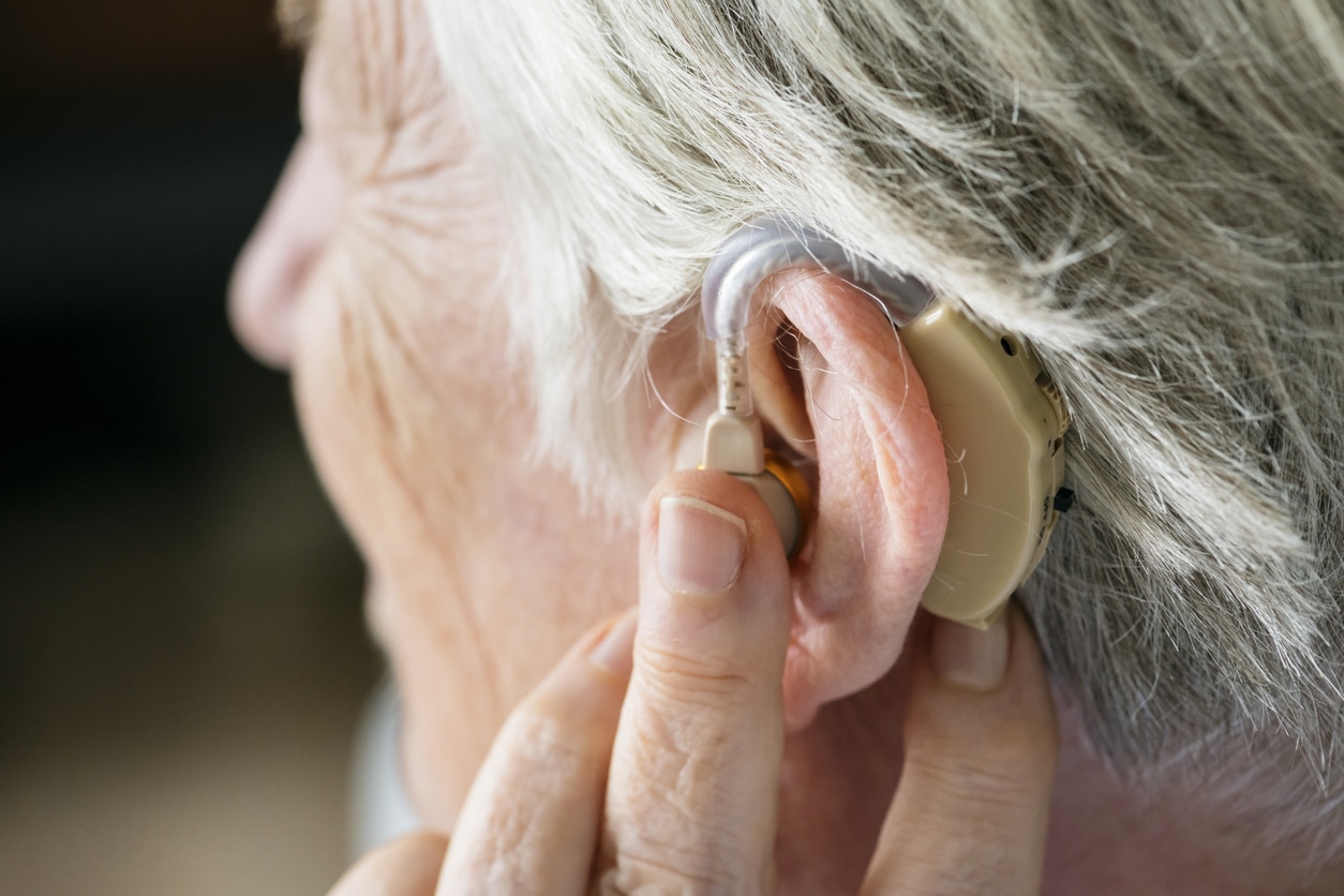Woman touches hearing aid